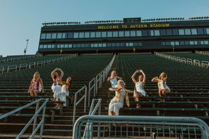 Friends celebrate on stadium steps during a sunset photoshoot.