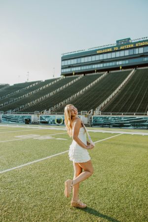 A person dances joyfully on the green turf of a football stadium.