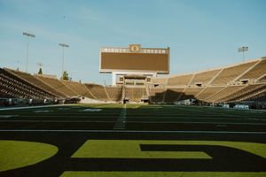 Empty stadium seats and field at University of Oregon's Autzen Stadium on a sunny day.