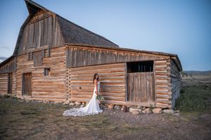 Rustic wedding photo featuring an old wooden barn in mountain setting.