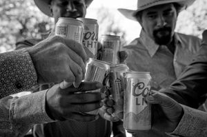 Wedding guests toasting with beer cans in casual outdoor celebration.