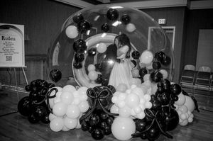 Black and white photo of couple under balloon arch with black and white balloon decorations.