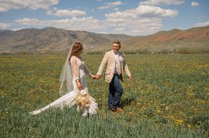 Wedding photo session in a scenic mountain meadow filled with wildflowers.