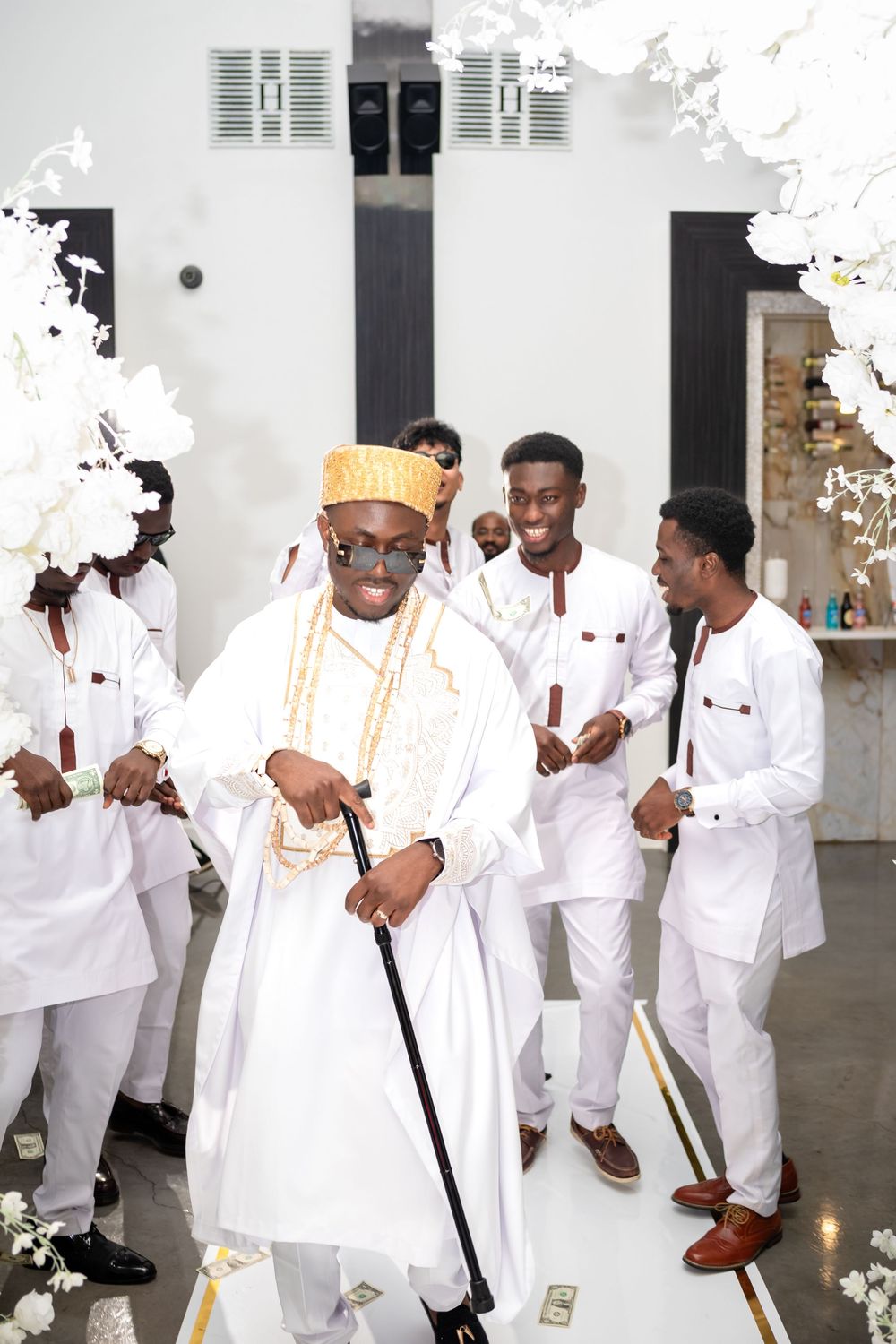A group of people dressed in all white traditional attire dancing and celebrating at a formal event.