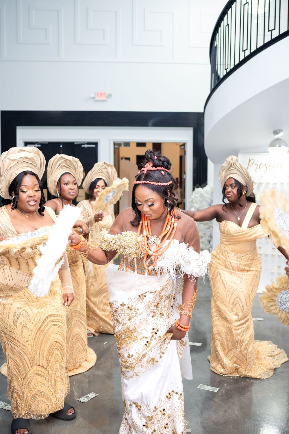 Group of wedding guests in gold attire dancing and celebrating at a reception party.