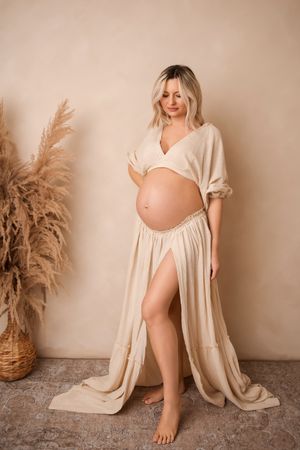 Artistic maternity photo series in neutral tones featuring flowing fabric and pampas grass decorative elements.