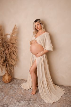 A series of maternity photos featuring an expectant mother in a flowing cream dress against a neutral backdrop with pampas grass decor.