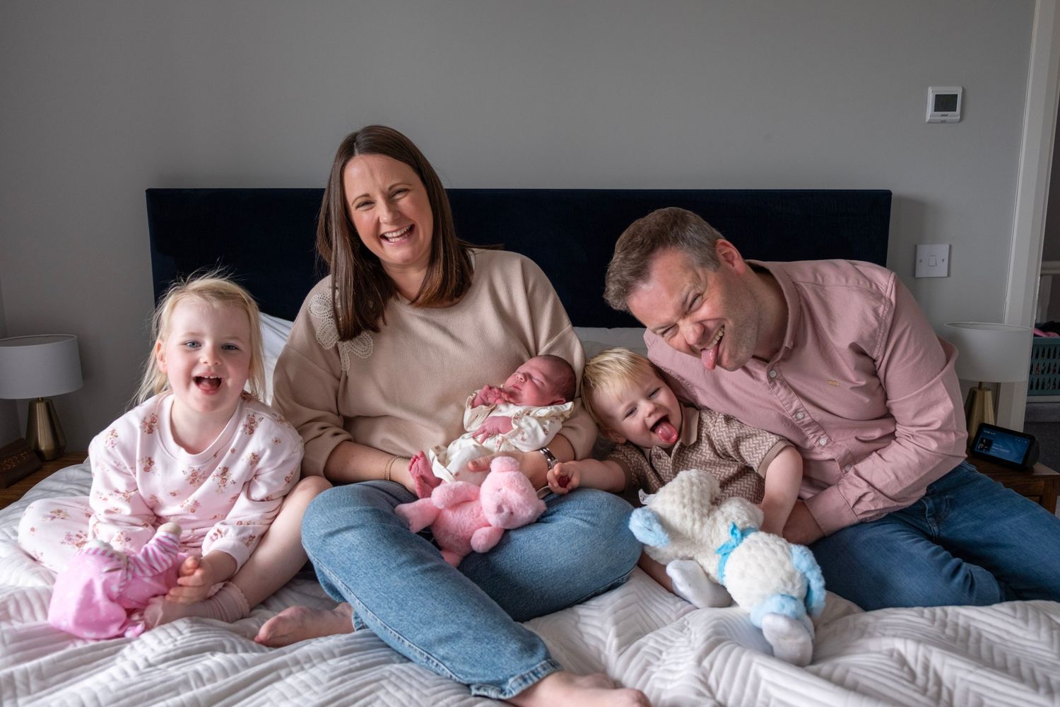 A sequence of five similar photos showing people lying down together on a white bed wearing pink and blue clothing.