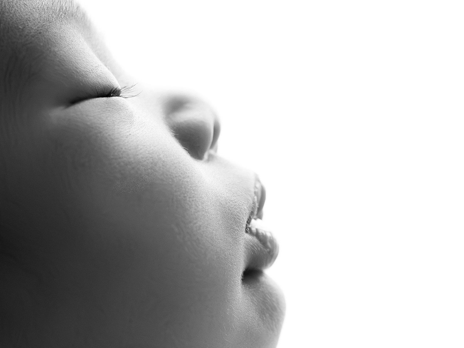 A close-up black and white photograph shows a person's face in a serene, sleeping pose.