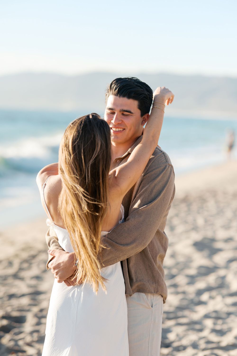 A couple embraces on a sunny beach as they share romantic moments together in three sequential photos.