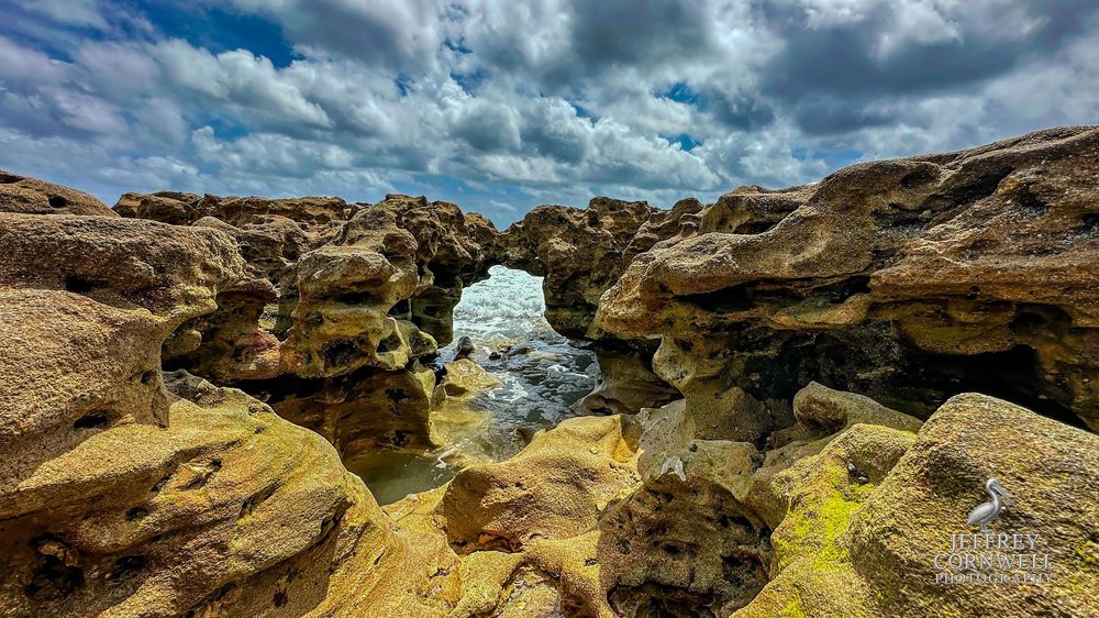 Panoramic view of weathered limestone cliffs along the coastline with dramatic cloud formations.