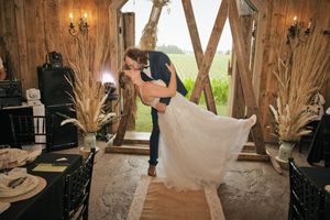 Marié portant sa femme dans ses bras pour un baiser dans la grange des Jardins d’Alex et Jennie à Laterrière, Saguenay.