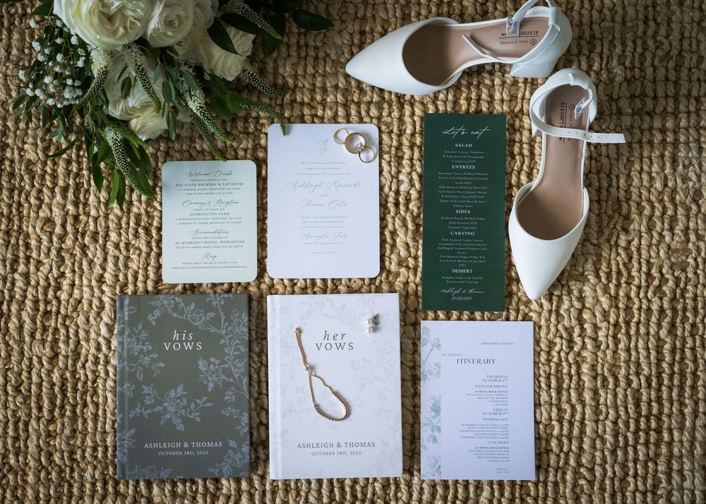 Wedding stationery flat lay featuring green and white invitations on textured background.