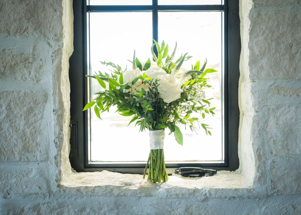Stone wall interior with three windows letting in natural light and green plants on windowsills.
