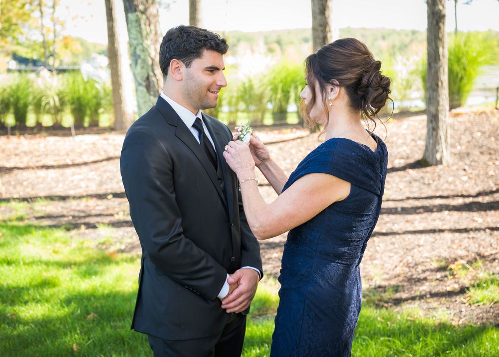 A formal moment between two people in elegant attire standing among trees on a sunny day.