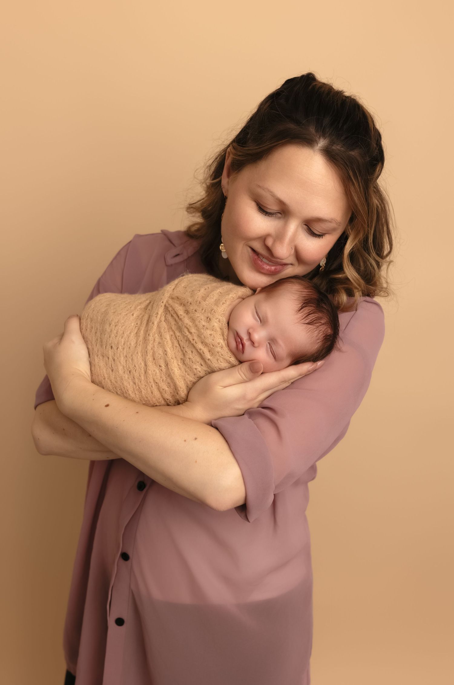 Lovely mama cradles her wrapped newborn daughter during a studio session with Somerset Portraits, a Culpeper-area baby photographer.