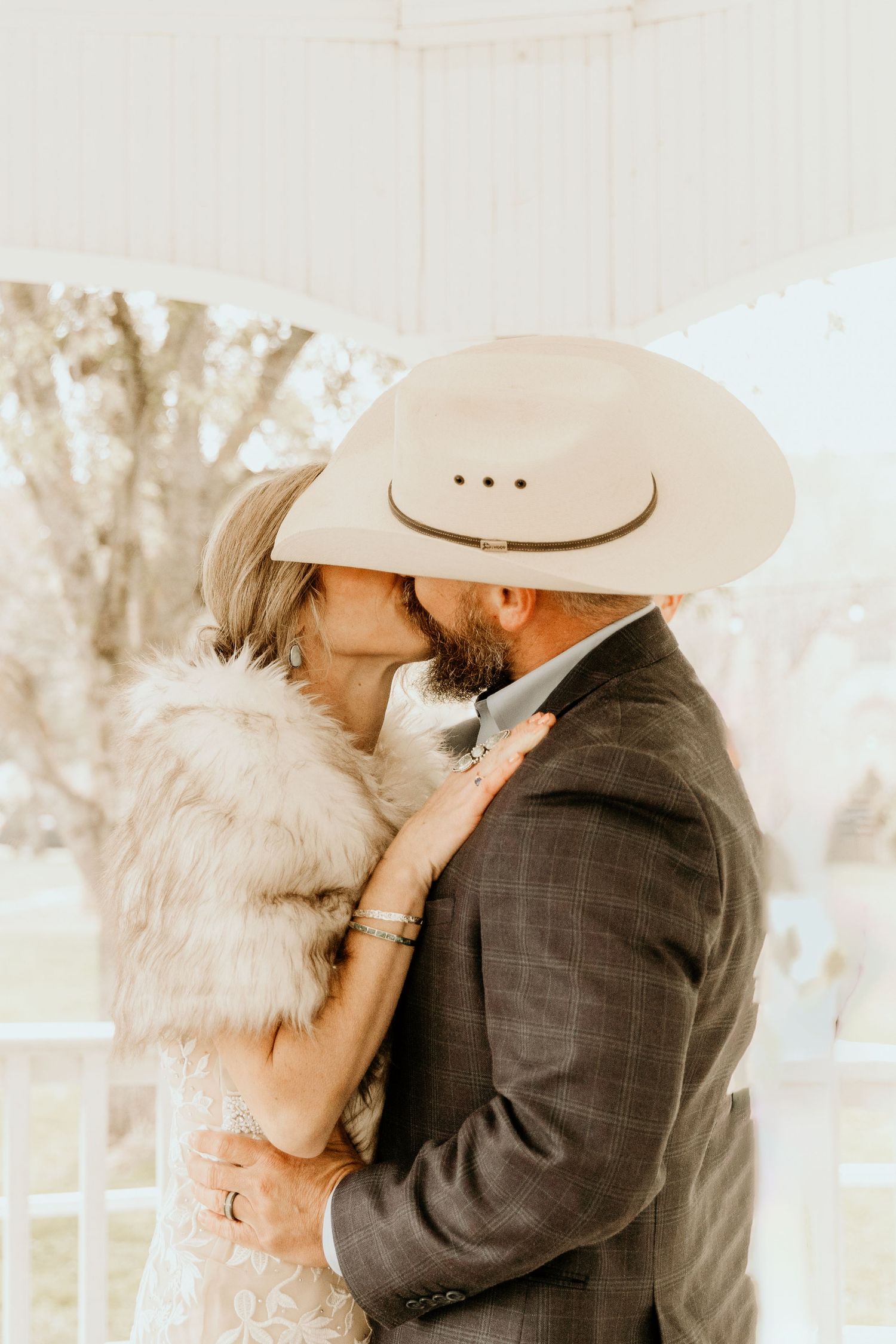 Romantic couple in western attire share intimate kisses across three connected images in sepia toned outdoor setting.