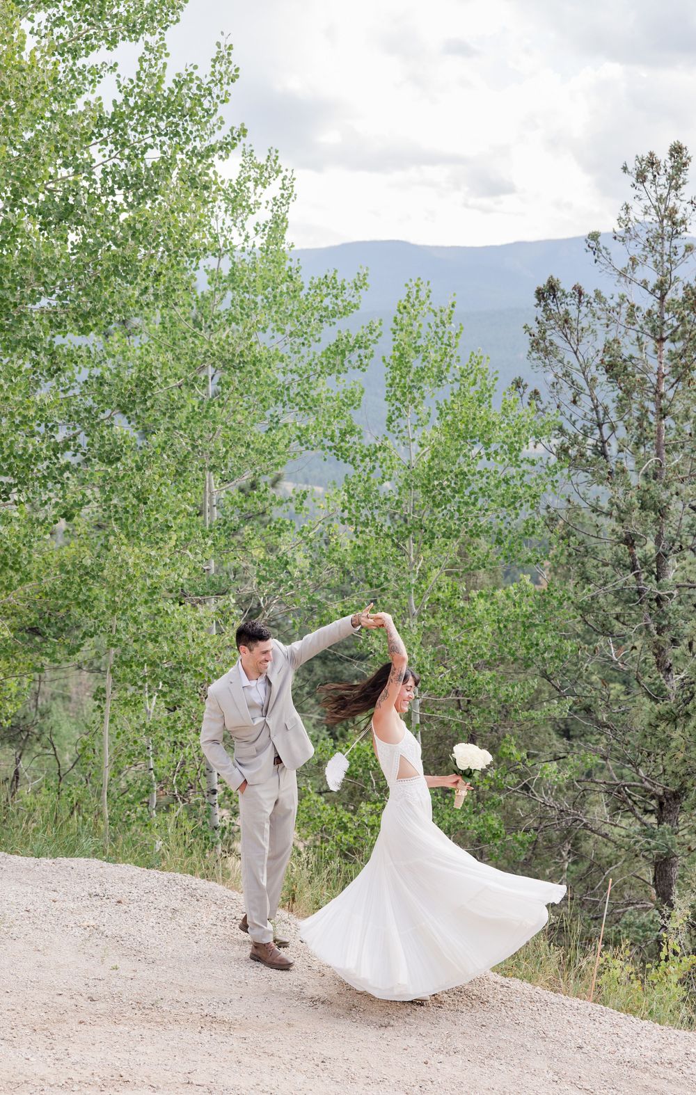 A couple dancing on a mountain path surrounded by aspen trees and scenic views.