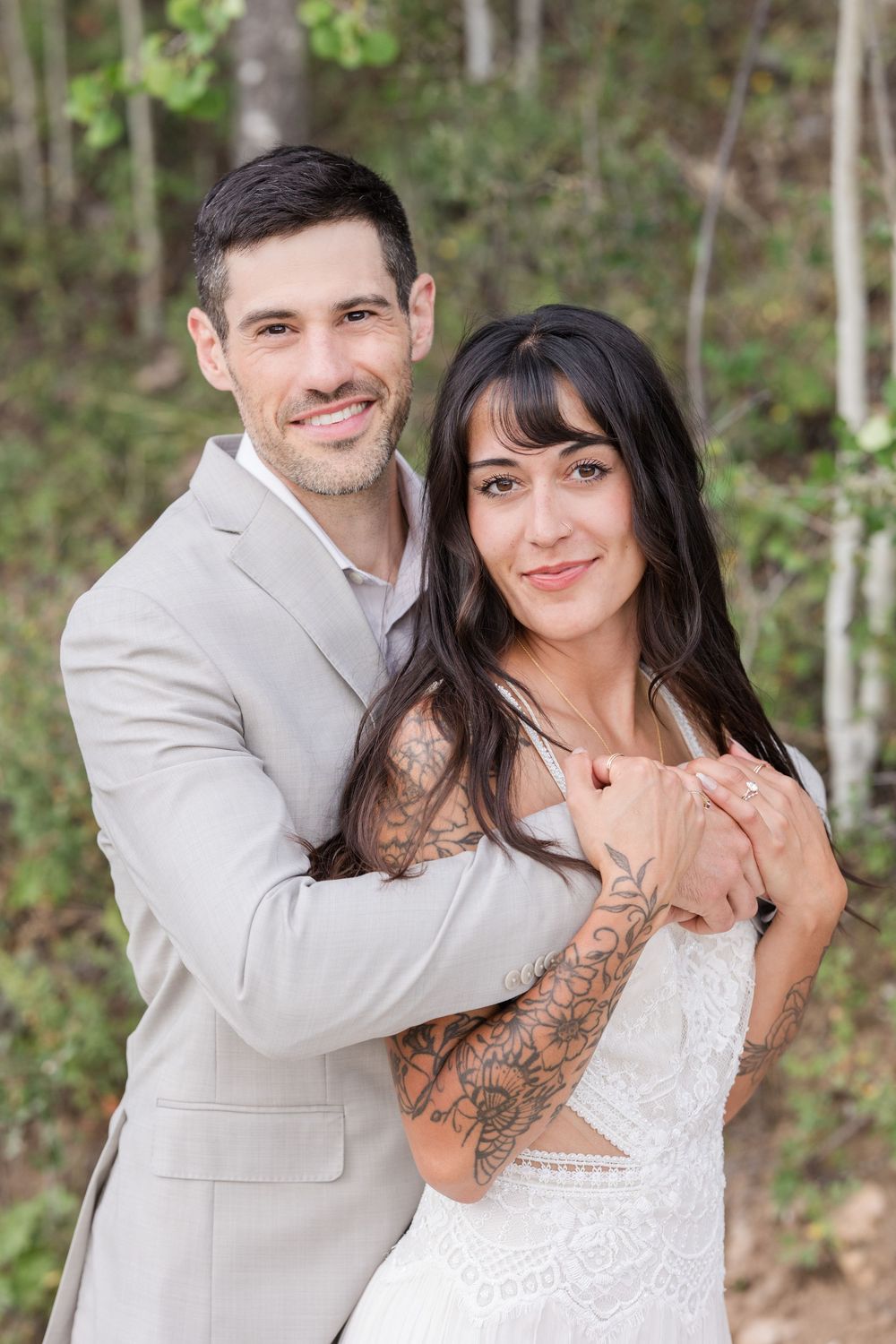Romantic outdoor portrait of newlyweds embracing against a natural forest backdrop.