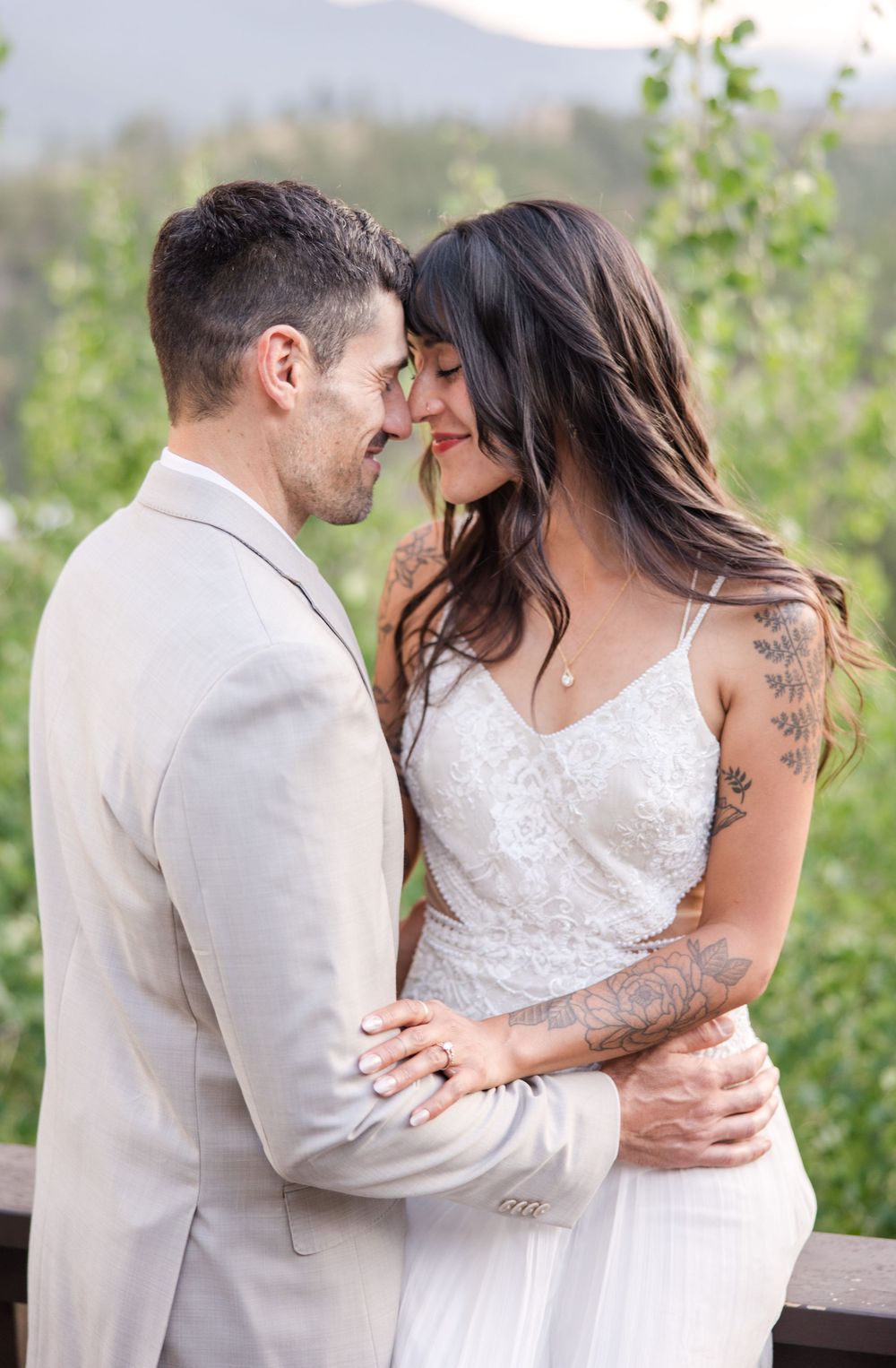 A romantic moment between a couple in a white wedding dress and light suit embracing outdoors.
