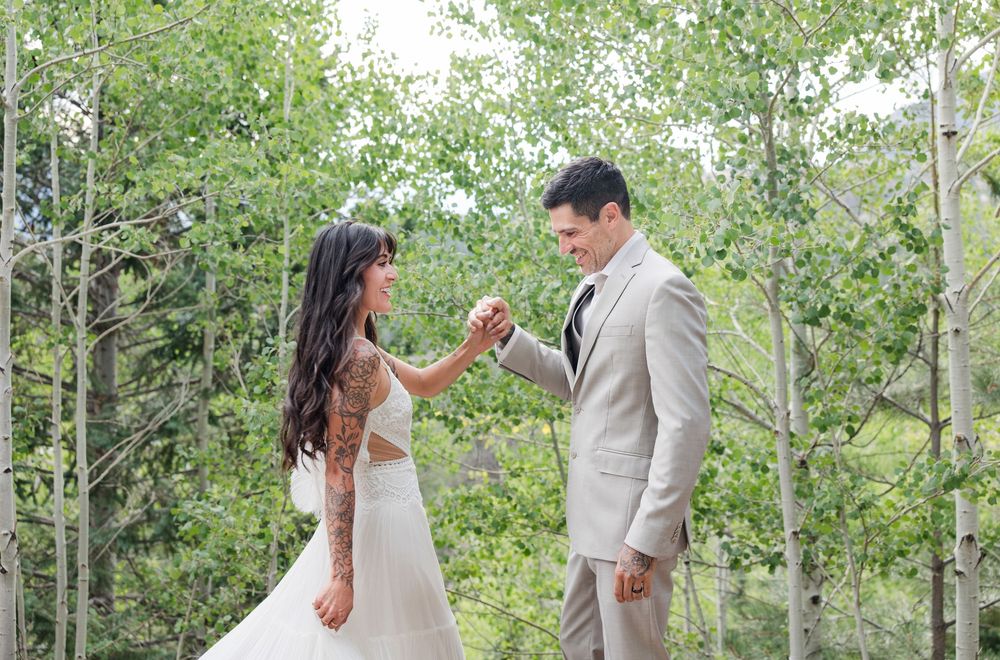 Newlyweds sharing romantic moments along a path surrounded by green aspen trees.