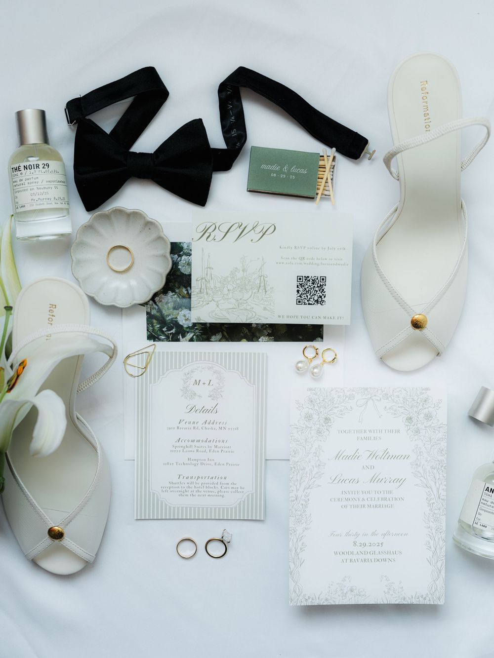 Wedding invitation suite flatlay with white florals, ribbons and elegant stationery details.