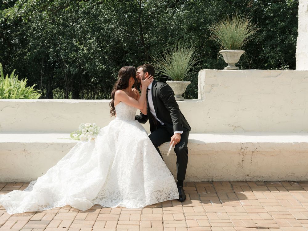 A sequence showing elegantly dressed figures posing together on an outdoor patio with flowing white fabric.