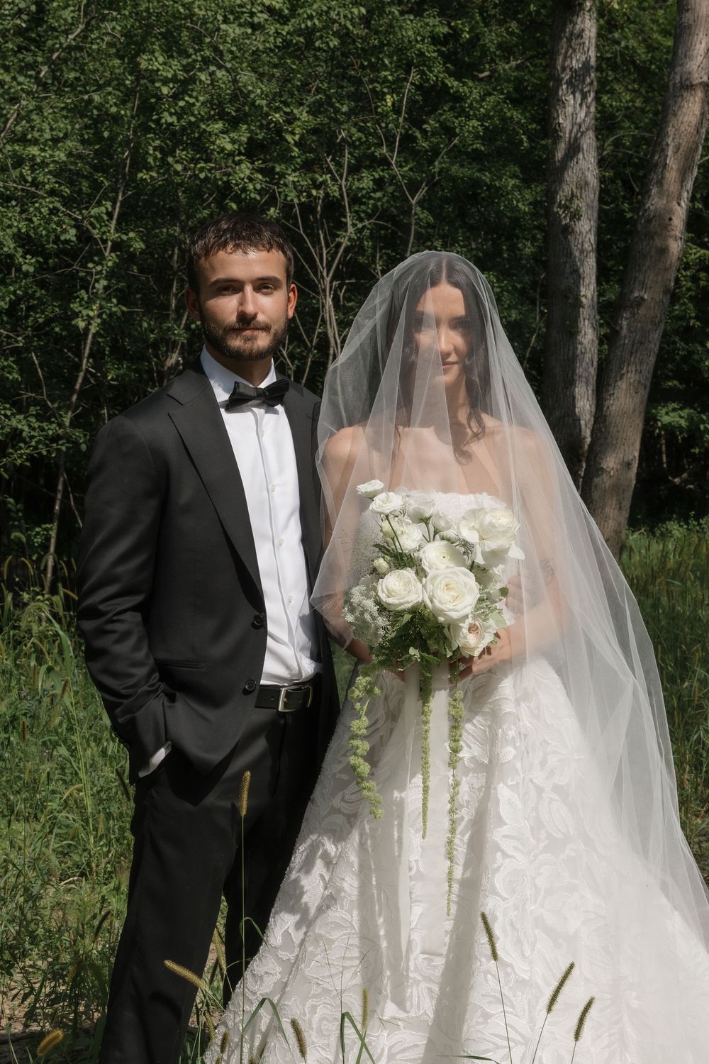 Wedding couple posing in a lush green forest setting.