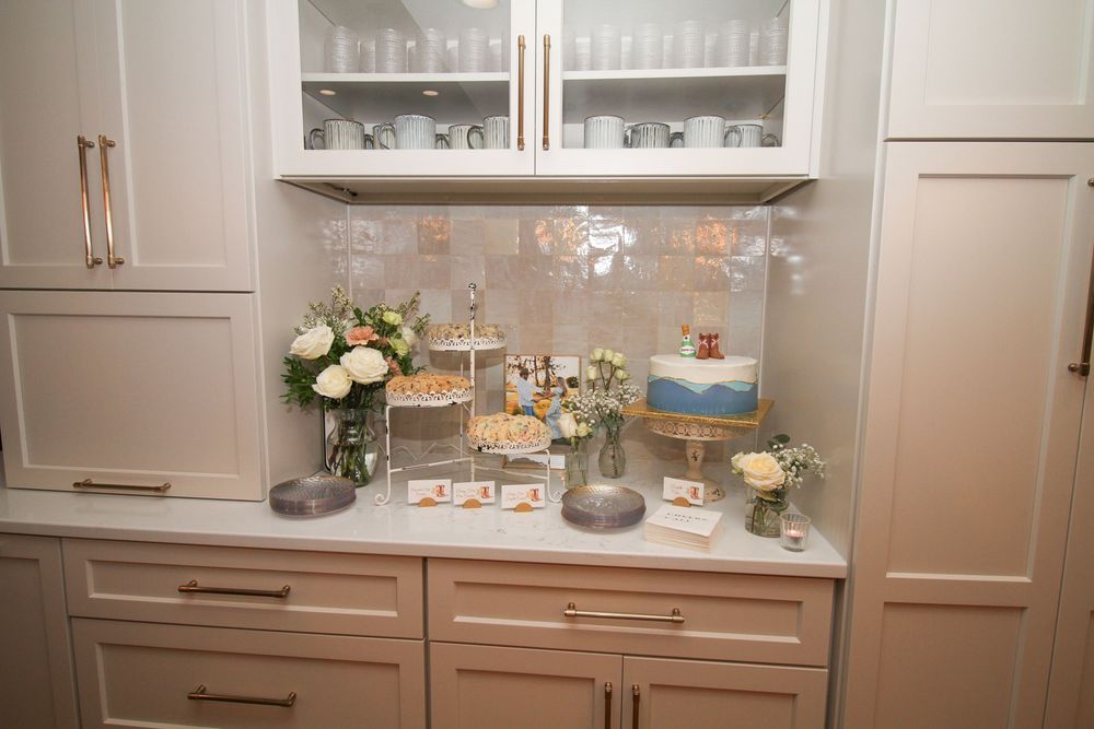 Elegant kitchen interior with glass-front cabinets displaying glassware and dishware on illuminated shelves.
