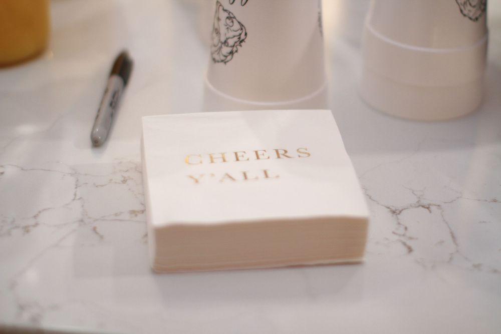 White place cards with gold lettering are arranged on a marble surface beside decorative elements at a formal event.