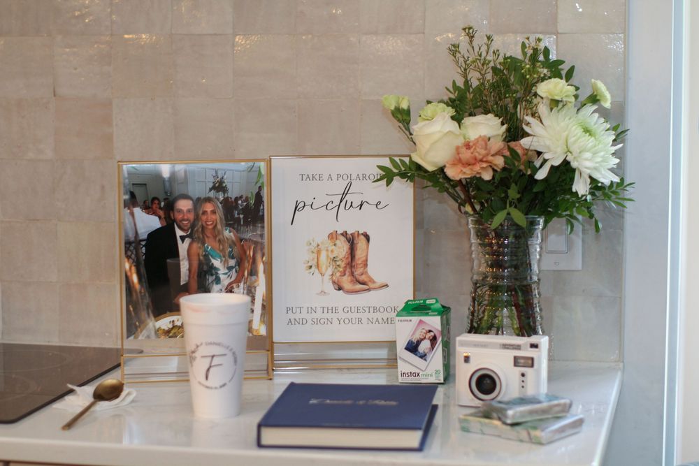 Elegant white shelving display with wedding decor items, framed prints, and fresh floral arrangements.