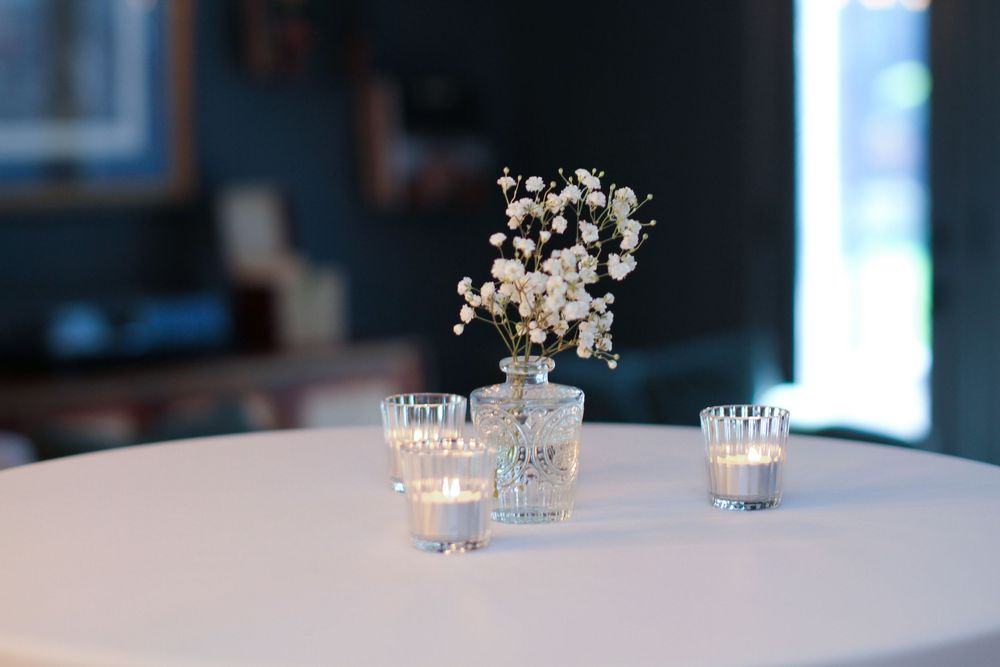White floral centerpiece arrangements with glass votives illuminate an elegant wedding reception table.