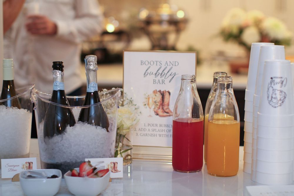 A drink station setup at an event with assorted beverages, including bottles chilling in ice and colorful juice mixers.