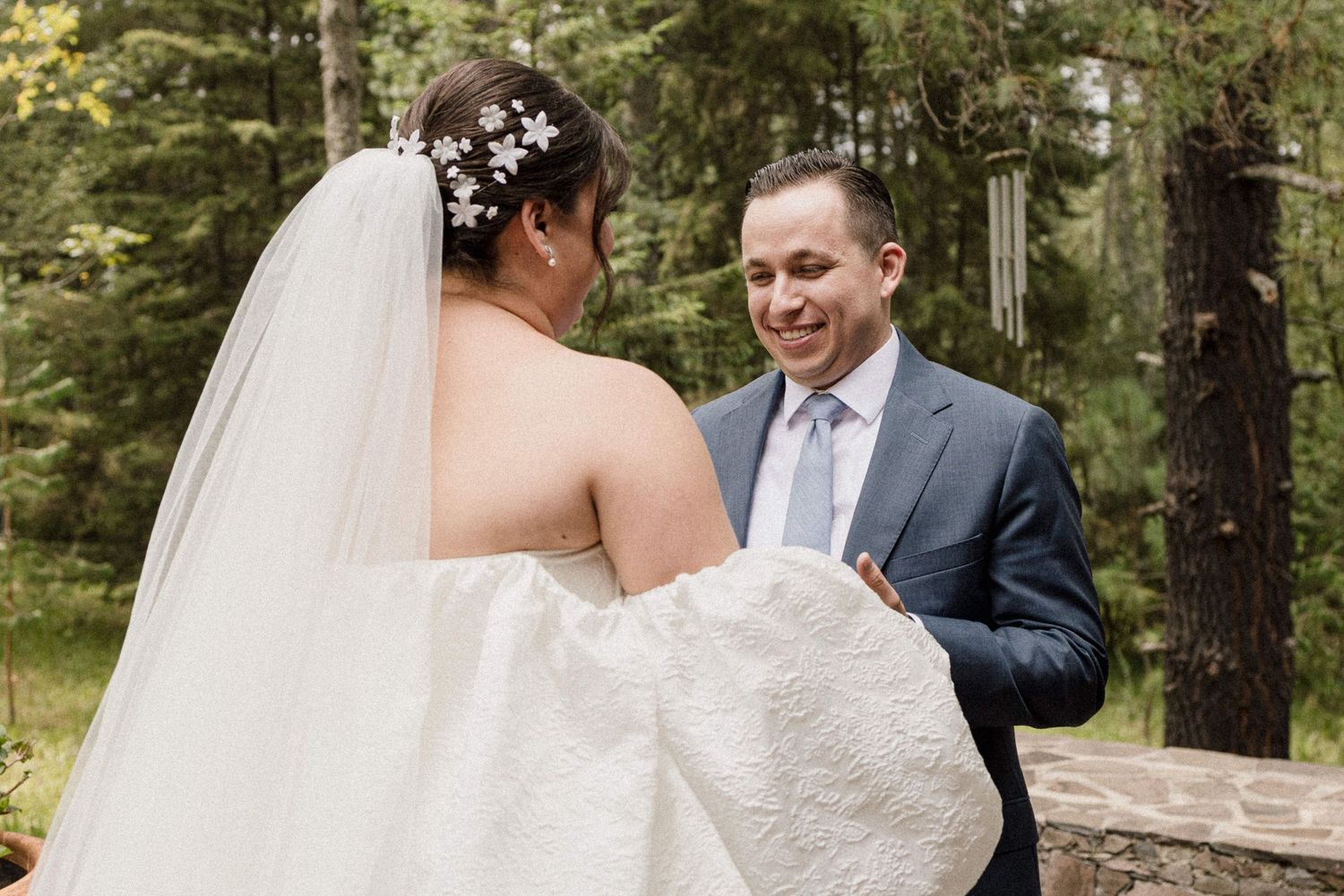 Romantic wedding couple sharing a joyful moment in a serene forest setting.