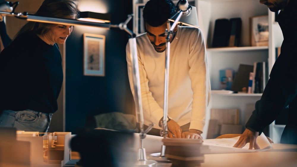 People collaborating on projects in stylish office with warm lighting and modern workspaces.