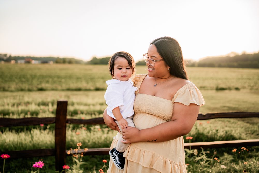 Warm sunset light illuminates a family gathering together in a scenic meadow with wildflowers.