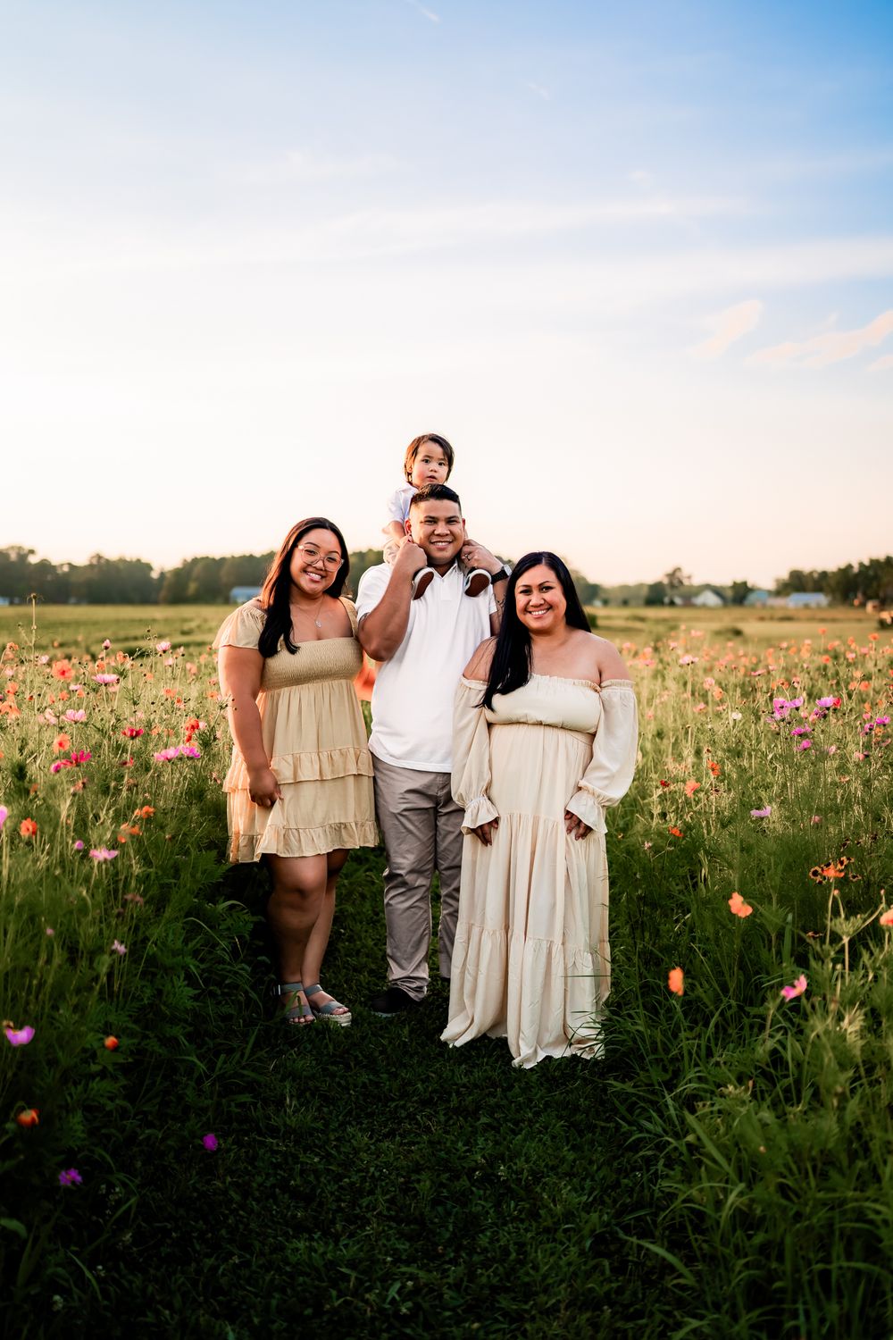 Family enjoying a sunset photoshoot in a meadow filled with colorful wildflowers.