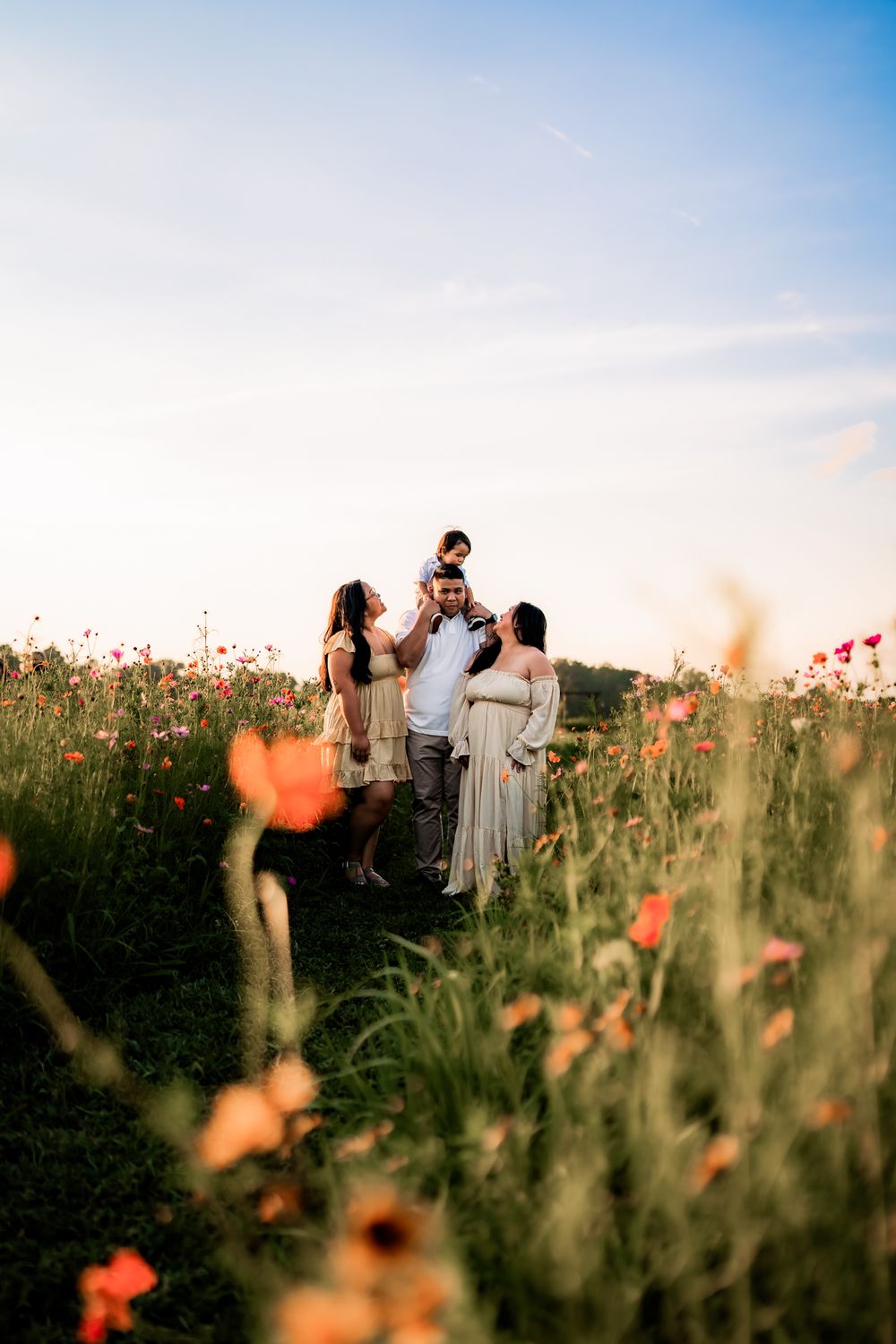 People in light-colored dresses gather in a dreamy poppy field at sunset.