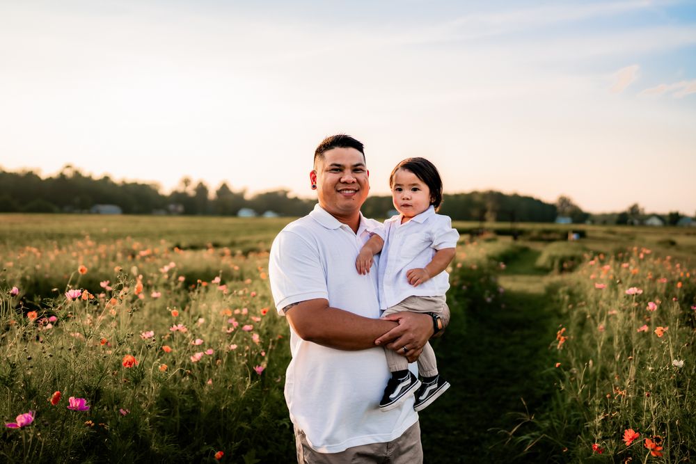 Family portrait session in a blooming wildflower meadow with soft natural lighting at dusk.