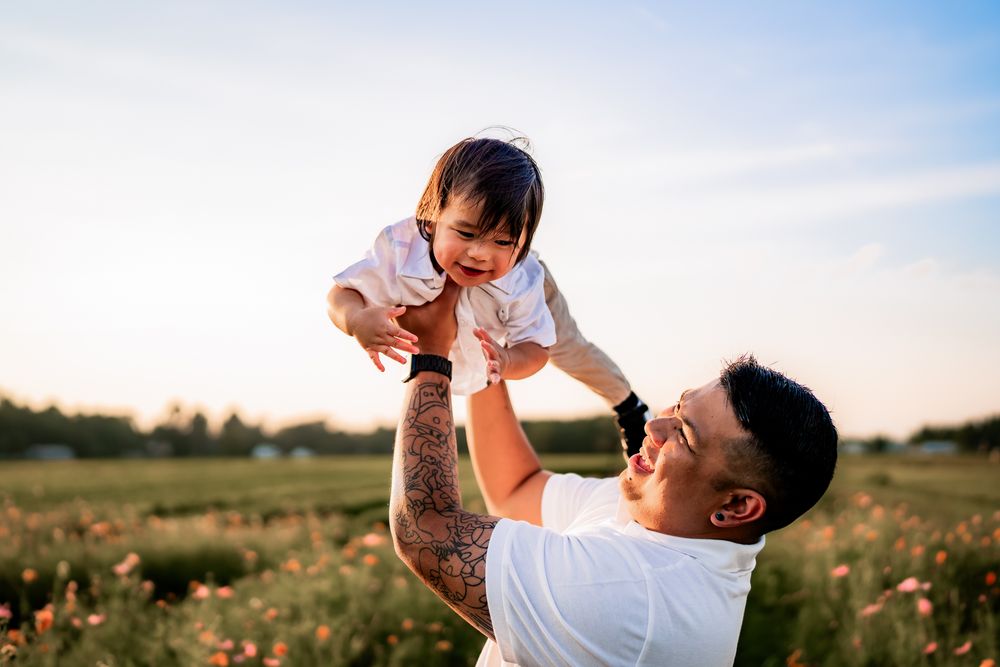 Parent and child sharing joyful moments while playing together in a sunlit meadow with wildflowers.