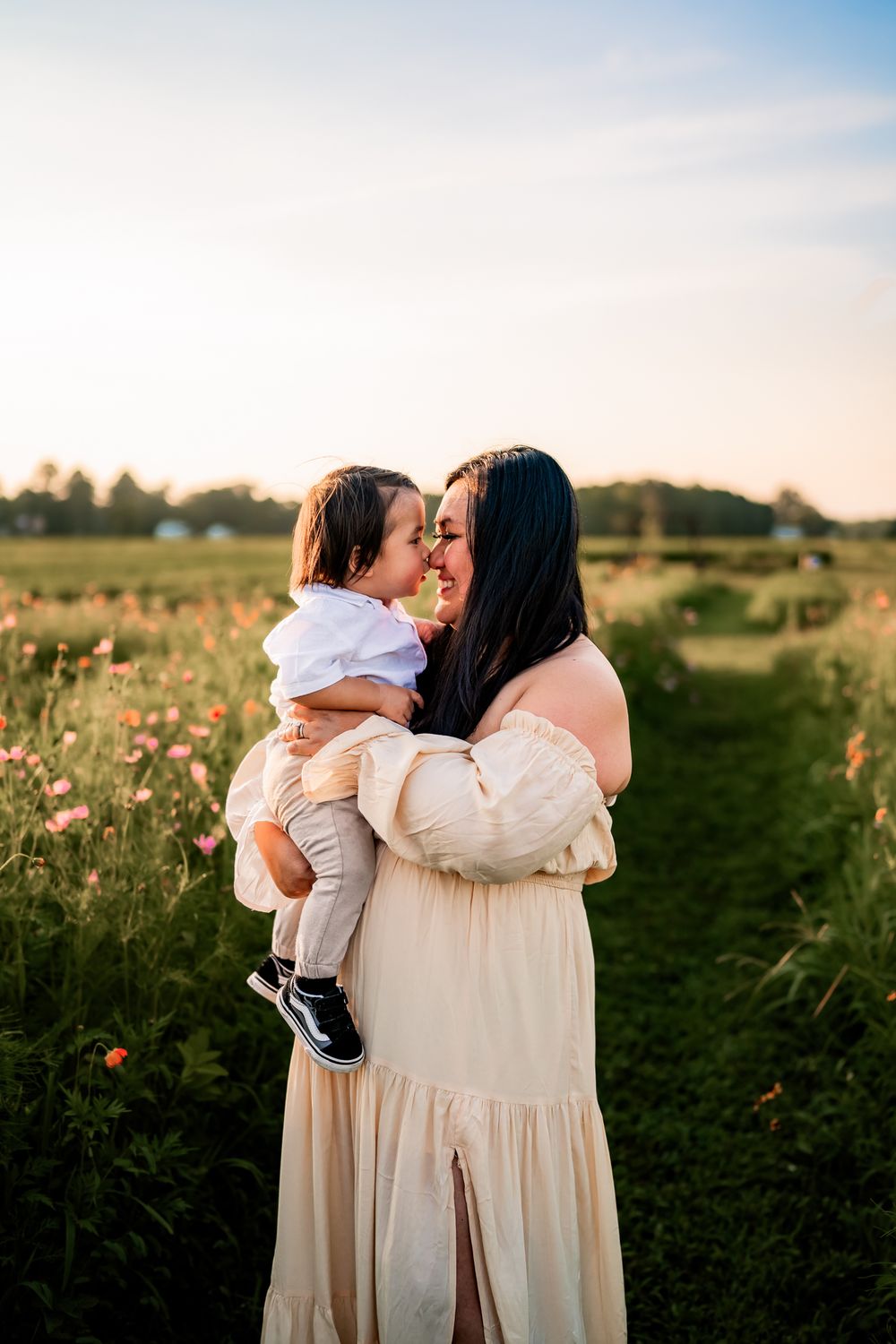 Family members share tender embraces in a wildflower field at dusk.