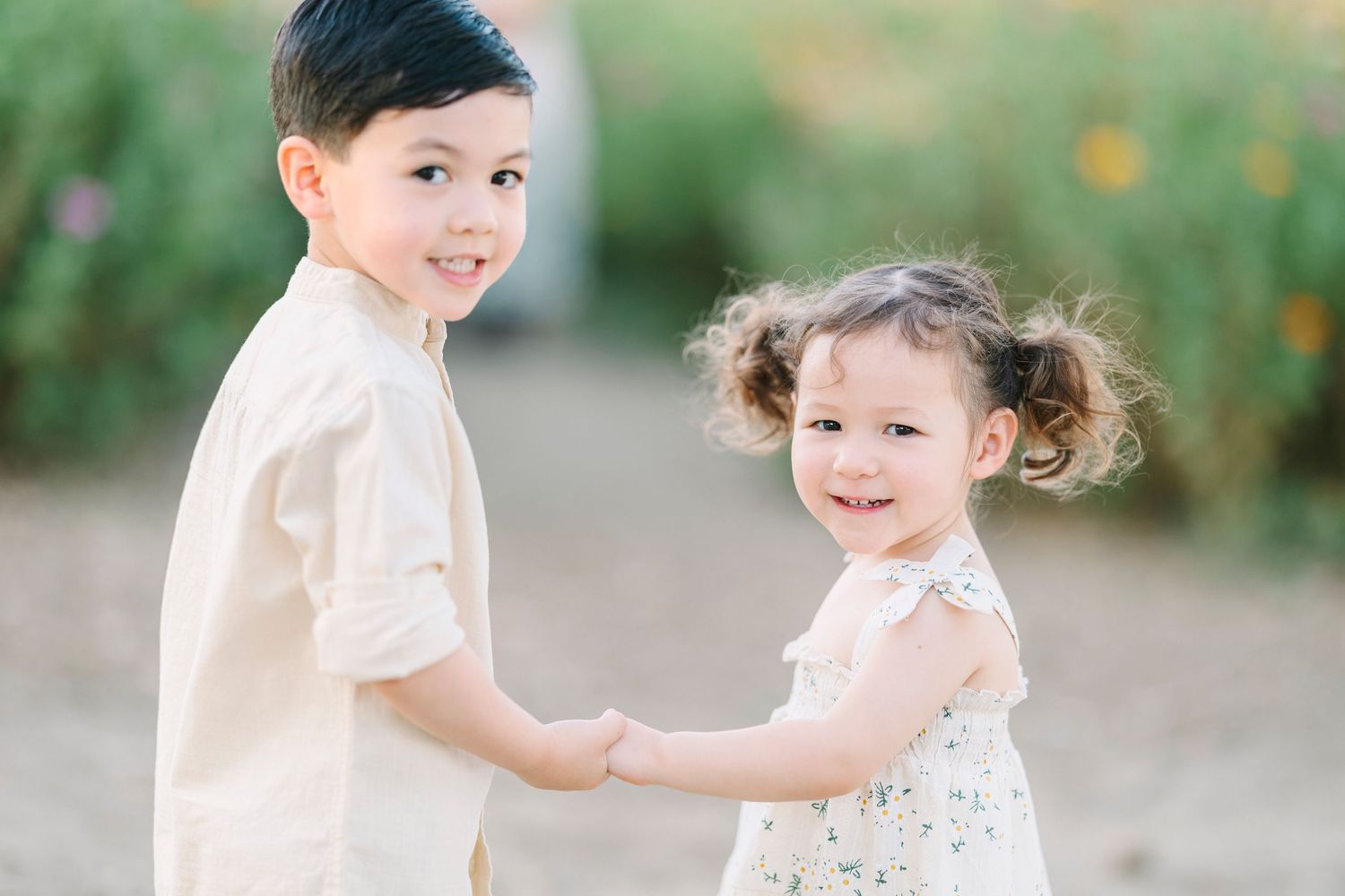 A joyful family plays together in a blooming flower garden during golden hour.