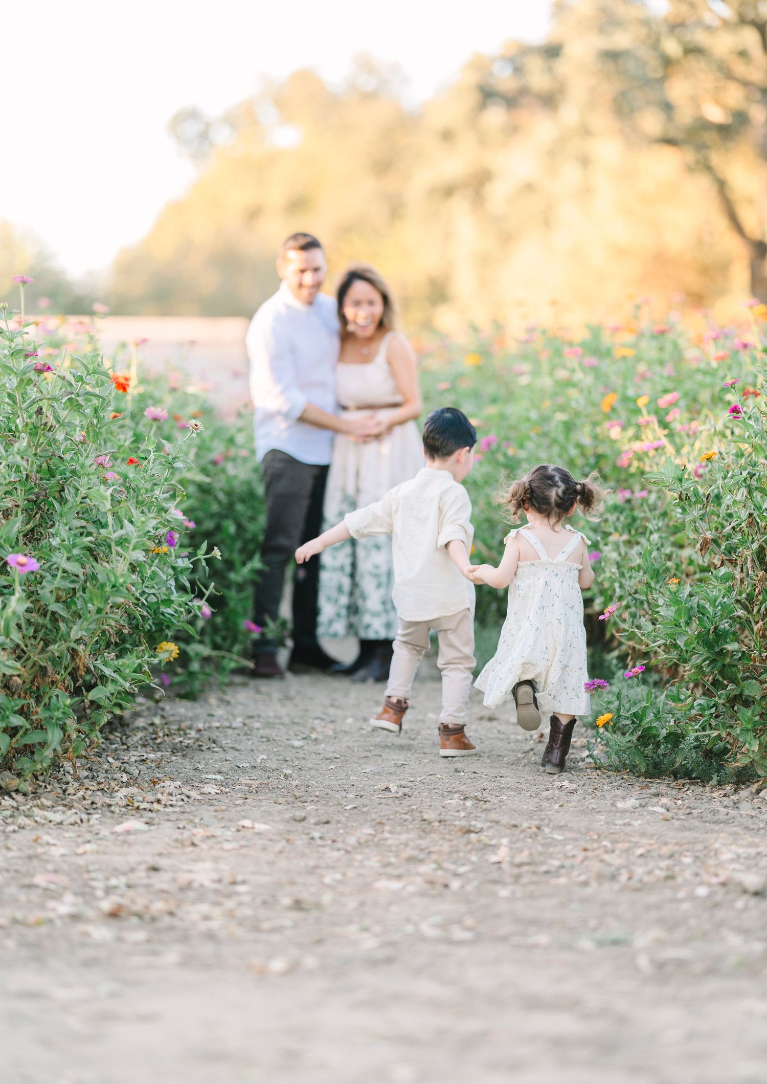 Candid family moments photographed along a garden path with flowering bushes.