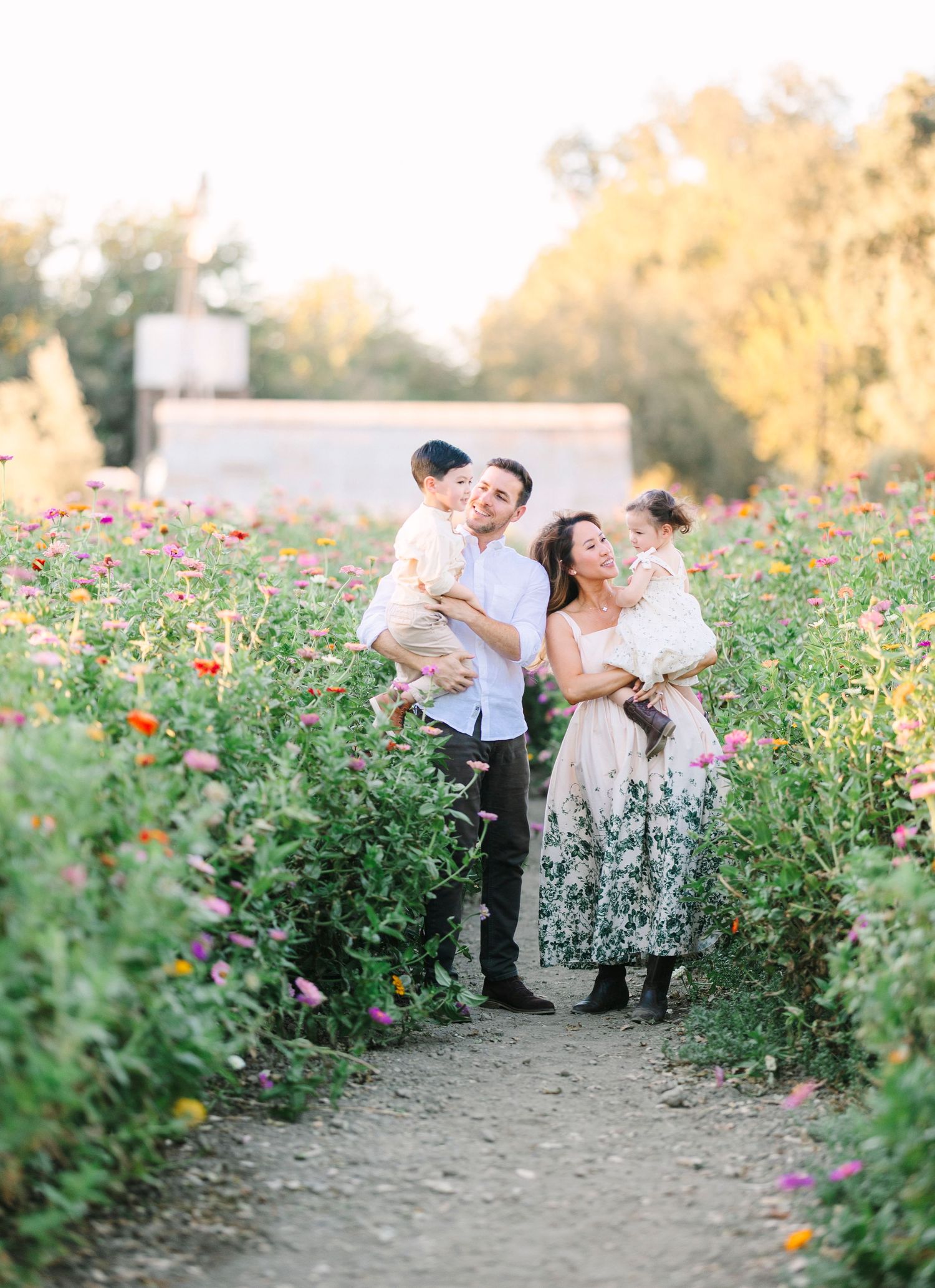 Family shares tender moments while walking through vibrant wildflower fields at sunset.