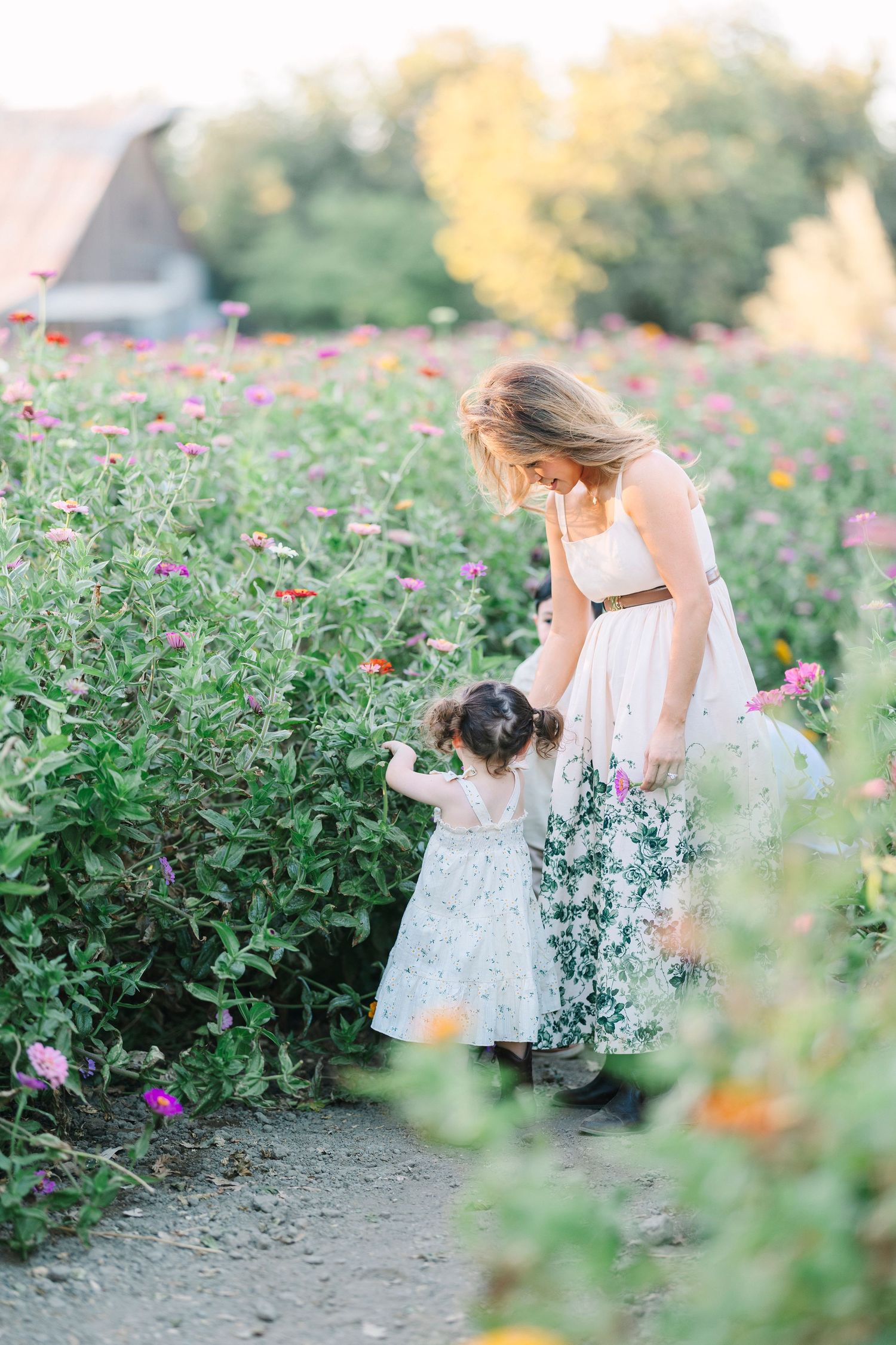 People walking and playing along a dirt path bordered by colorful wildflowers.