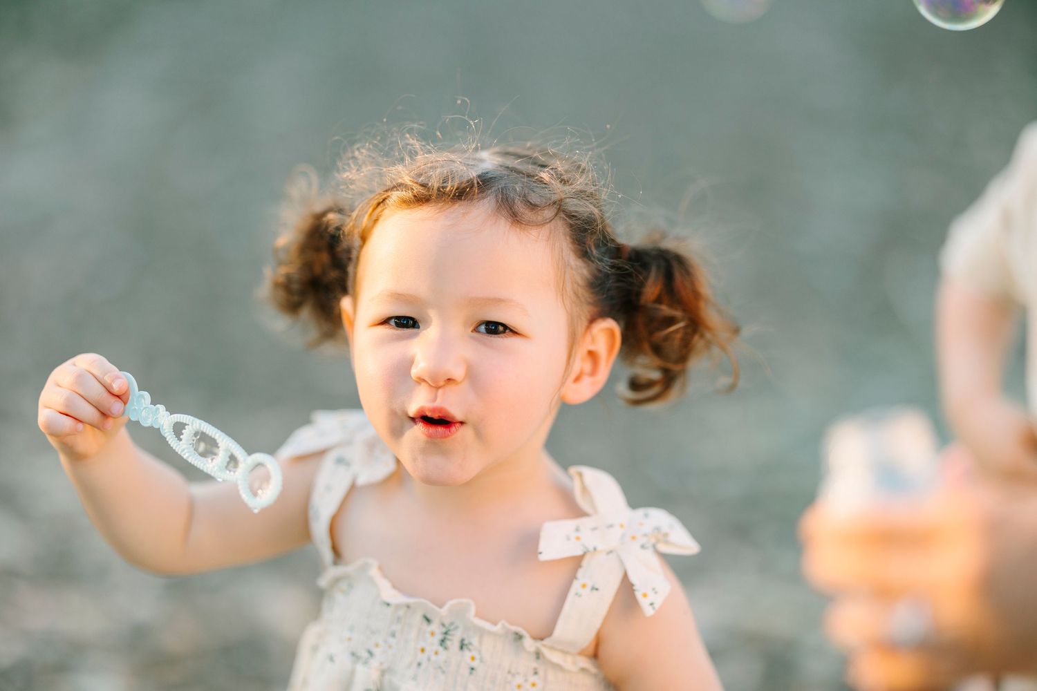 Bubbles float through the air as children play in an outdoor setting.
