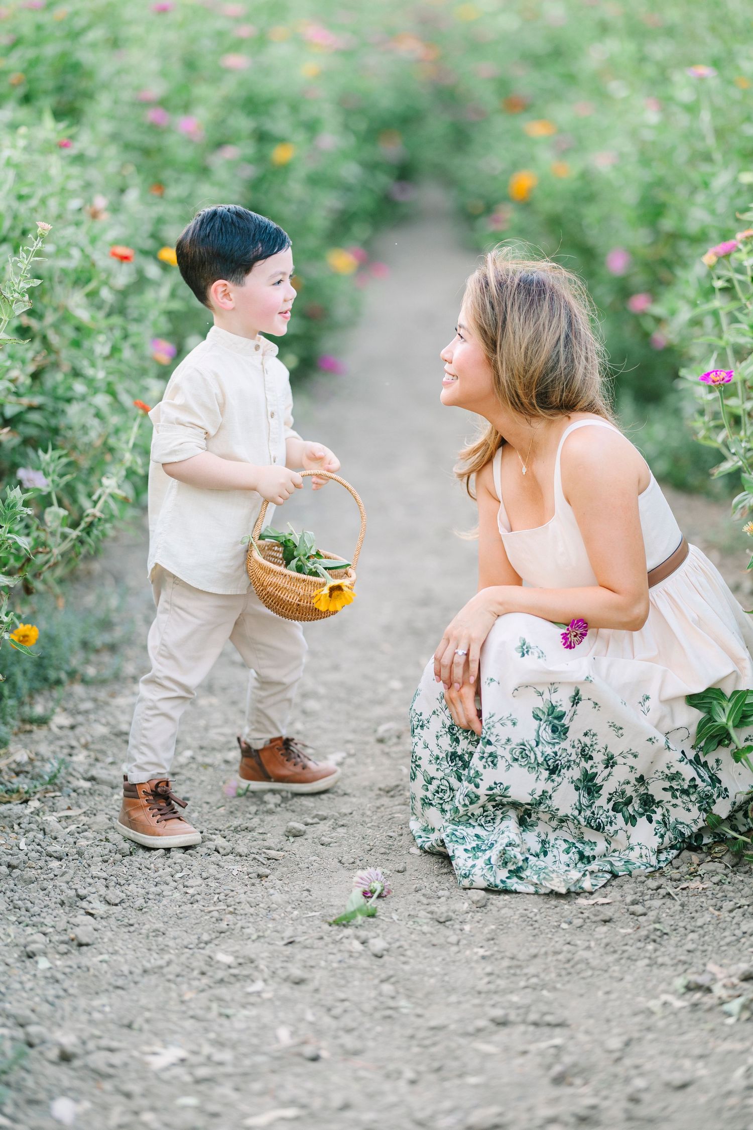 Mother and child share playful moments on a garden path surrounded by flowers.