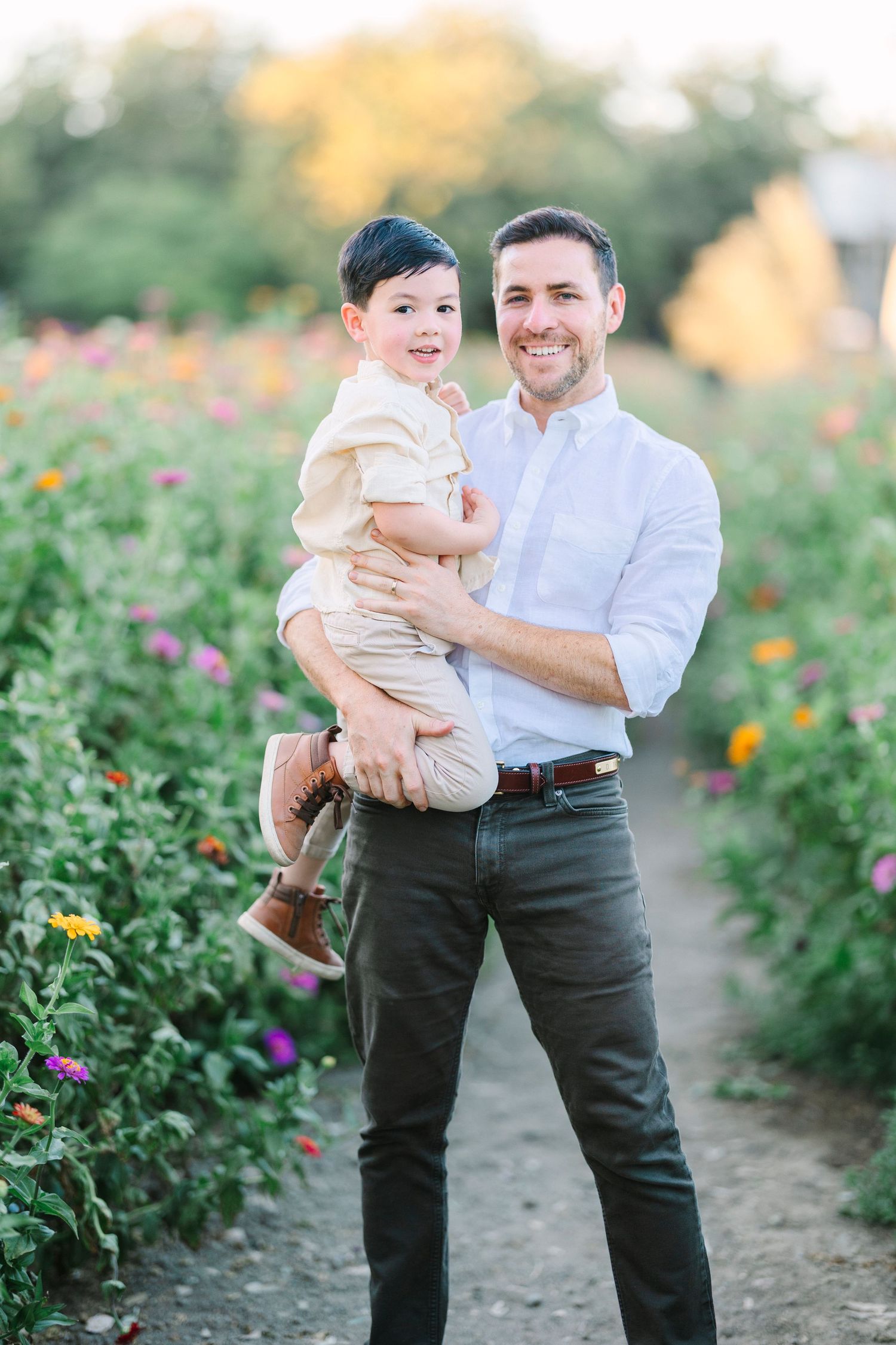 Two people share a joyful moment together in a garden filled with vibrant flowers.
