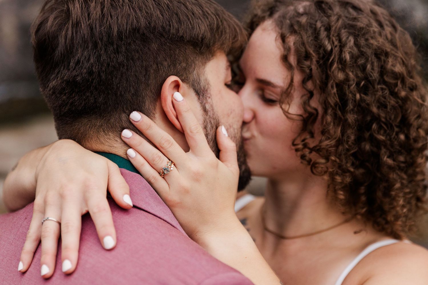 Close-up shot of two people sharing an intimate romantic kiss at what appears to be a wedding celebration.