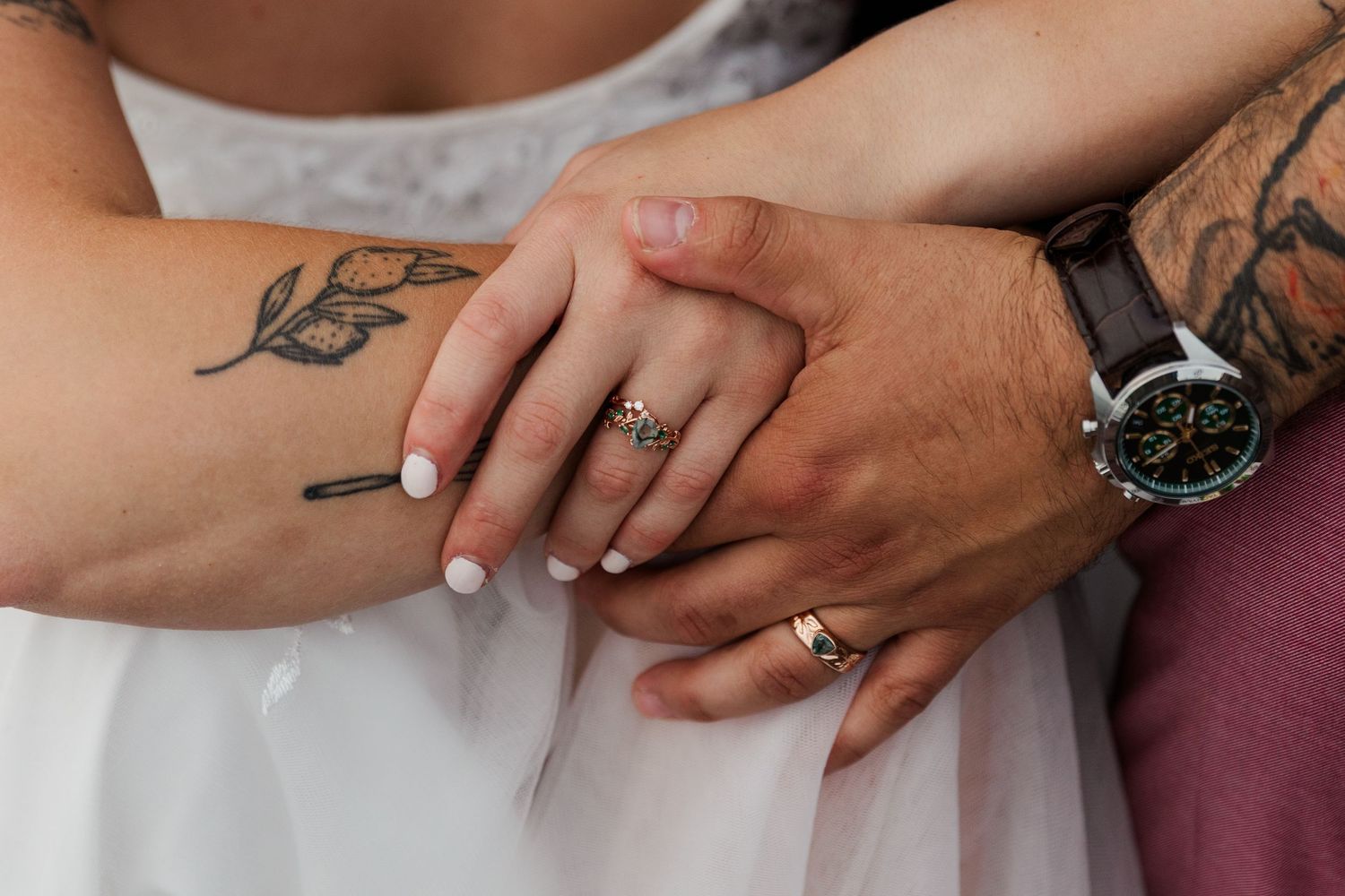 Two hands with engagement rings touch lovingly in a romantic moment.